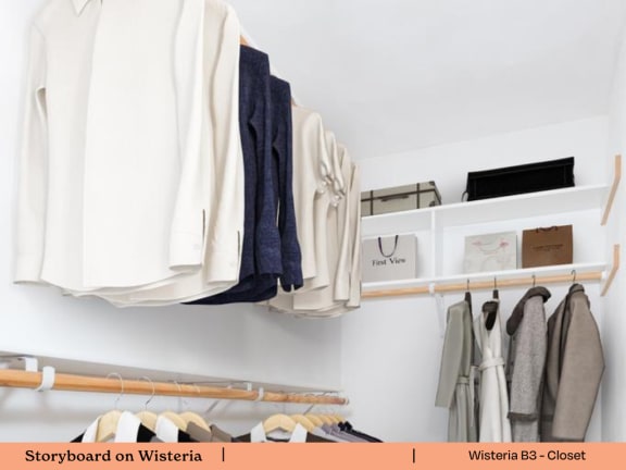 a white closet with clothes hanging on a rack and a shelf