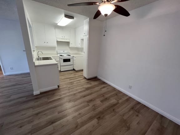 a living room and kitchen with wood flooring and a ceiling fan