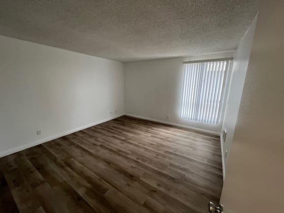 an empty living room with wood flooring and a window