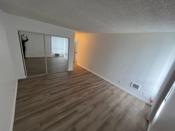 an empty living room with wood flooring and a mirrored closet