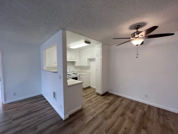 an empty living room and kitchen with a ceiling fan