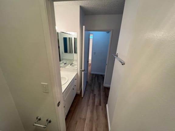 a bathroom with a sink and mirror and a hallway with a door to a bathroom