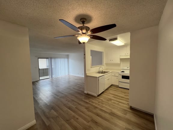 an empty living room and kitchen with a ceiling fan