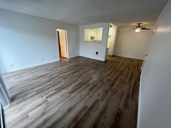 an empty living room with wood floors and a ceiling fan