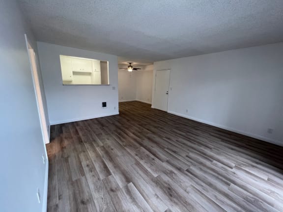 the living room and dining room of an empty home with wood flooring