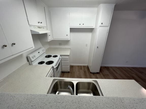 an empty kitchen with white cabinets and a stainless steel sink