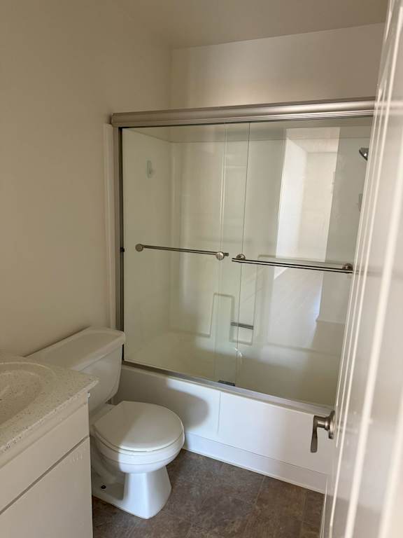 A white toilet sits next to a walk-in shower.