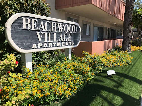 a sign apartments in front of flowers