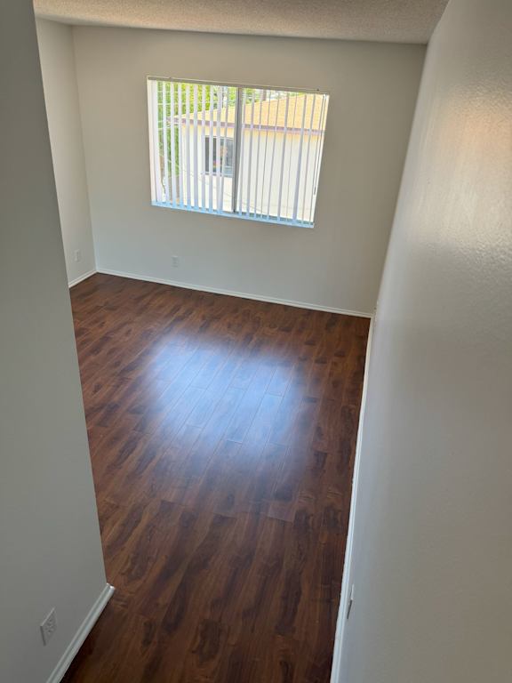 A room with wooden floors and a window with blinds.