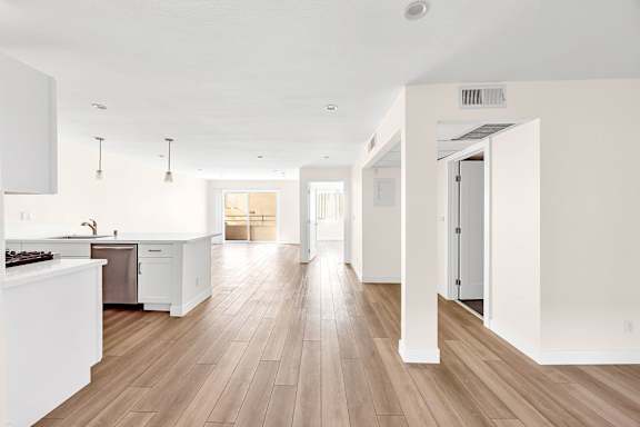 A kitchen with white cabinets and a wooden floor.