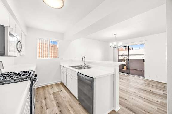 A modern kitchen with white appliances and wooden floors.