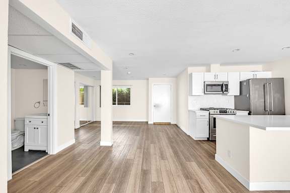 A kitchen with white cabinets and a wooden floor.