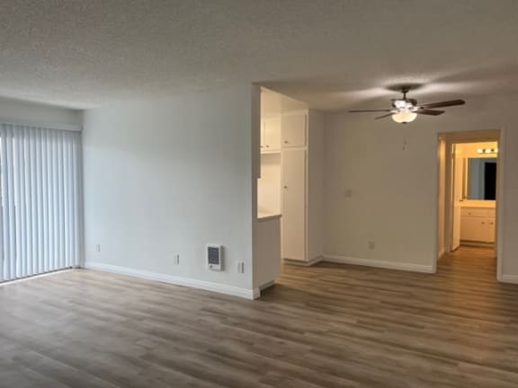 an empty living room with a ceiling fan and a window