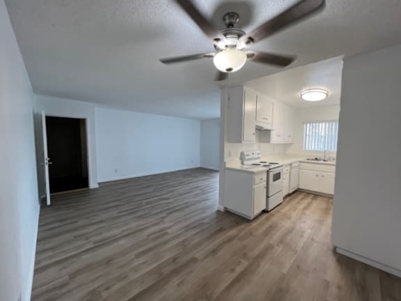 an empty kitchen and living room with a ceiling fan