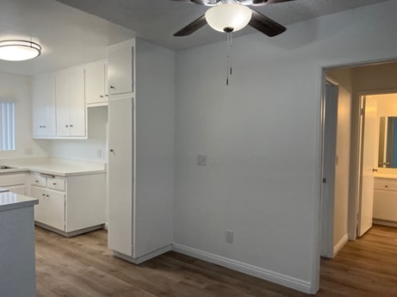 an empty kitchen with white cabinets and a ceiling fan