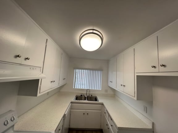 an empty kitchen with white cabinets and a sink