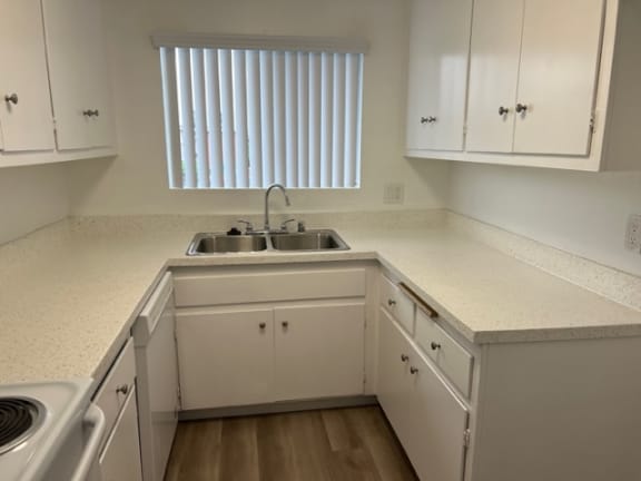 an empty kitchen with white cabinets and a sink