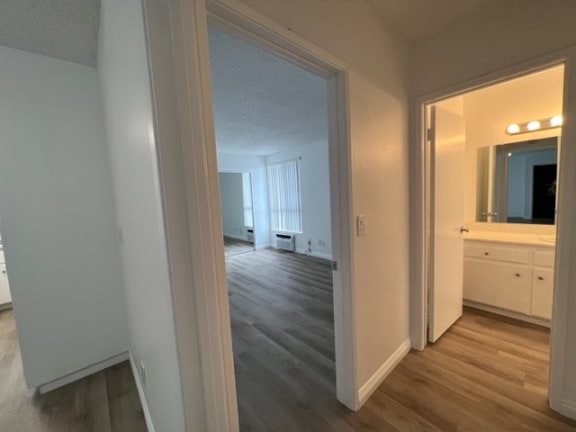 an empty living room with a hallway to a bedroom and a bathroom