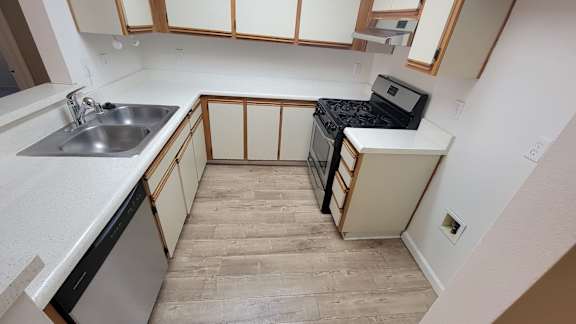 A kitchen with a stove, sink, and cabinets.