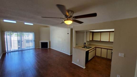 A room with a ceiling fan and a kitchenette.