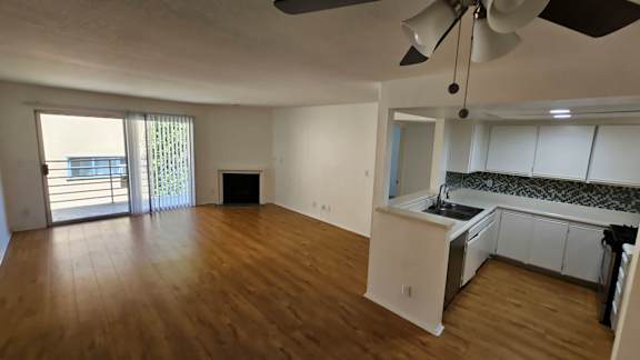 A room with a ceiling fan and wooden flooring.
