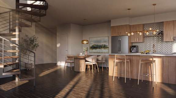 A modern kitchen with wooden floors and a staircase on the left side.