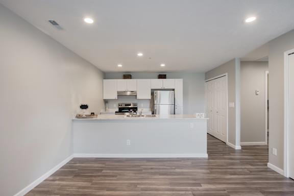 A kitchen with a white counter and a wood floor.