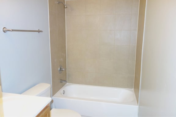 A white bathtub sits next to a toilet in a bathroom.