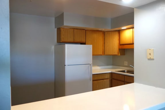 A kitchen with a white counter top and a stainless steel refrigerator.
