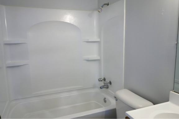 A white bathroom with a tub, toilet, and sink.