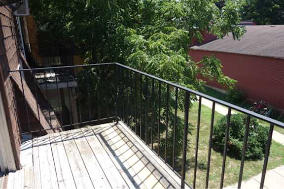 A balcony with a metal railing and a wooden floor.