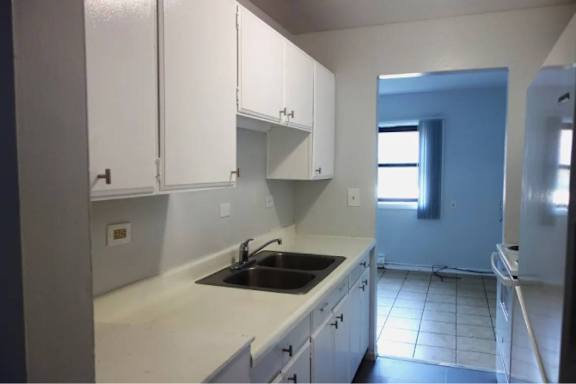 A kitchen with white cabinets and a black fridge.