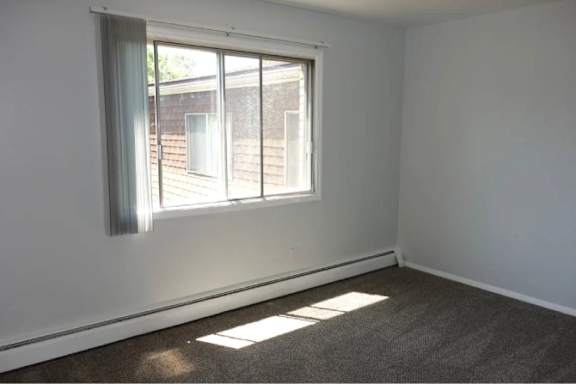 A room with a window and a carpeted floor.