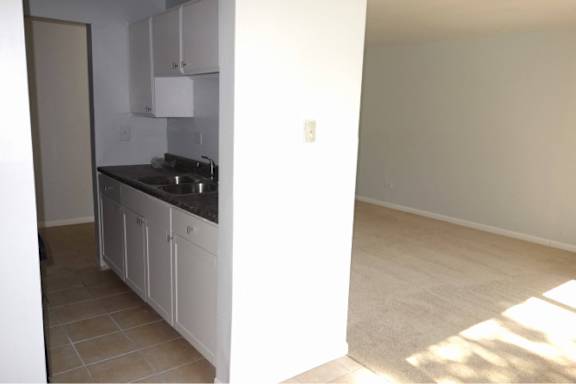 A kitchen with white cabinets and a black countertop.