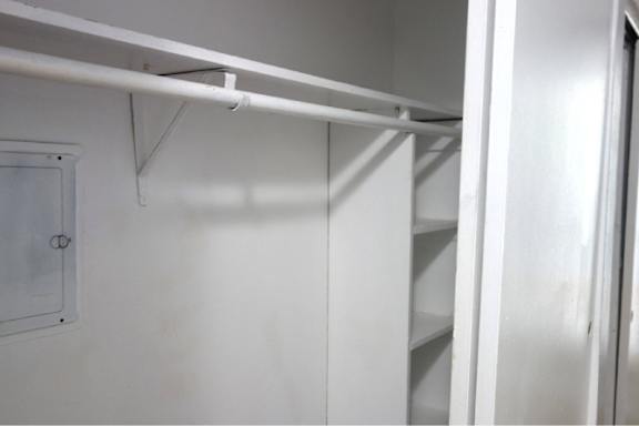 A white closet with a white shelf and a white door.