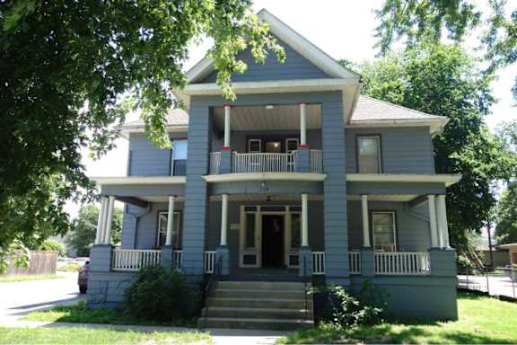 A two-story house with a front porch and stairs leading up to the entrance.