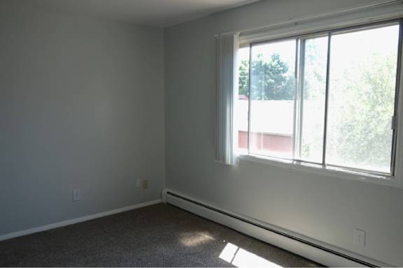 A room with a large window and a carpeted floor.