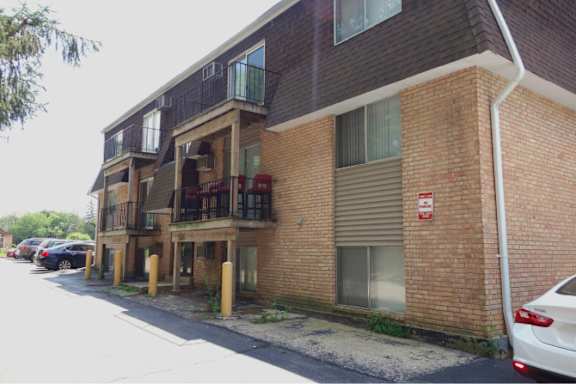 A red brick building with a white car parked in front.