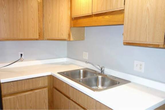 A kitchen with wooden cabinets and a white countertop.