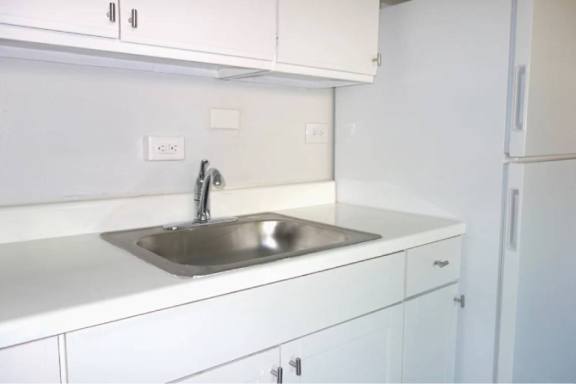 A kitchen with white cabinets and a stainless steel sink.