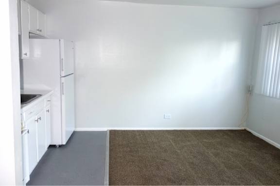 A kitchen with white cabinets and a refrigerator.