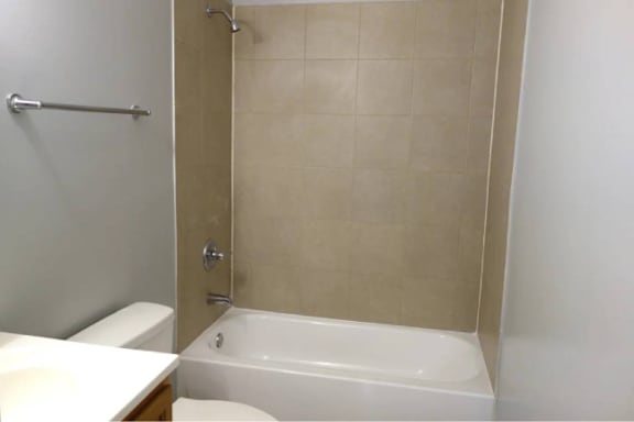 A white bathtub is in a bathroom with beige tiles.