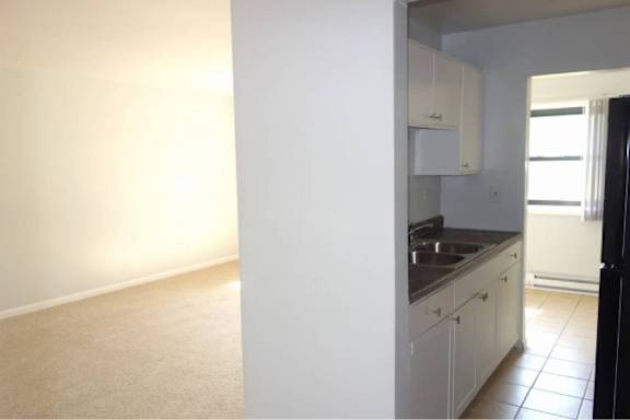A kitchen with white cabinets and a black refrigerator.