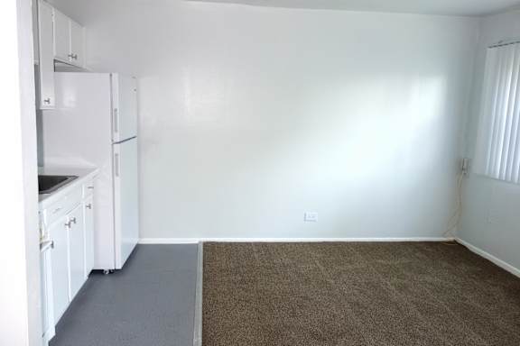 A kitchen with white cabinets and a refrigerator.