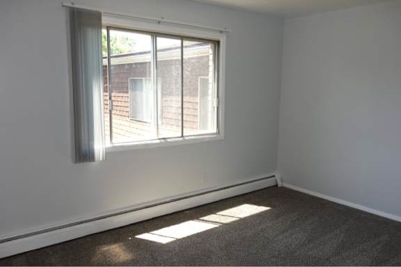 A room with a large window and a carpeted floor.