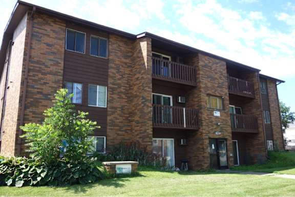 A brown brick building with a balcony on the second floor.