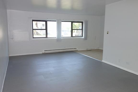 A large empty room with a window and a door.