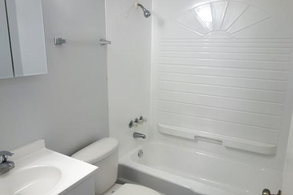 A white bathroom with a sink, toilet and bathtub.