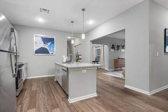 A kitchen with wood flooring and stainless steel appliances.