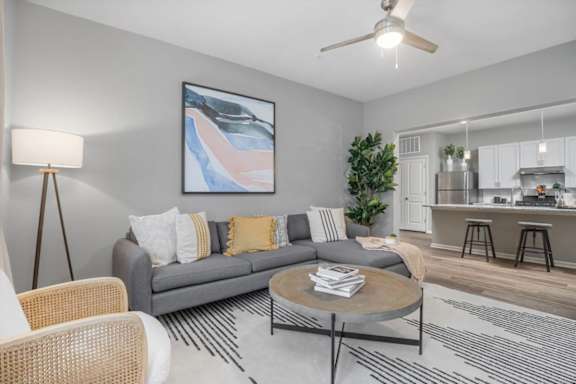 A living room with a grey couch, a round coffee table, and a painting on the wall.